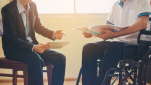 Michigan car accident lawyer image of injured crash victim in wheelchair reviewing documents with legal representative
