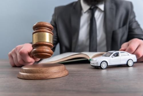 Michigan car accident lawyer concept image showing judge&rsquo;s gavel next to a model car representing legal action after a crash