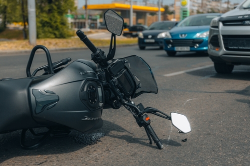 Michigan motorcycle accident lawyer image of fallen motorcycle on road after collision with traffic nearby