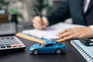 Michigan car accident lawyer image of paperwork and toy car representing insurance claim and settlement