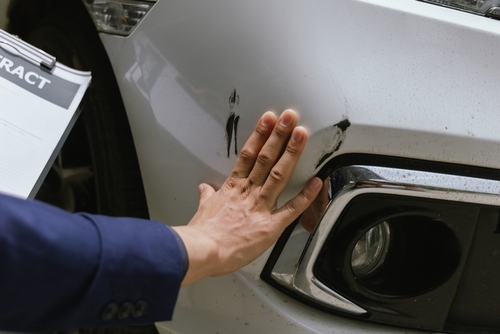 Michigan car accident lawyer image of person inspecting damage on a vehicle after a collision