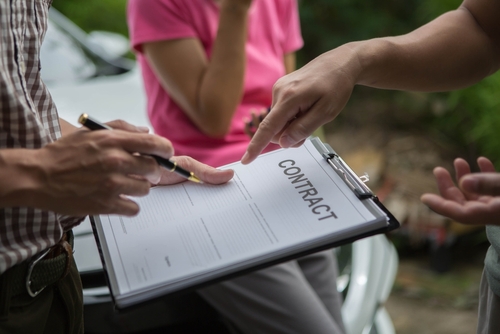 Michigan personal injury lawyer image of people reviewing and signing insurance contract after accident.