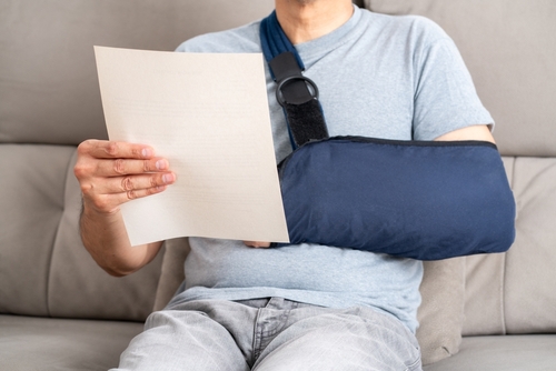 Michigan personal injury attorney image of injured person with arm in sling reviewing medical document