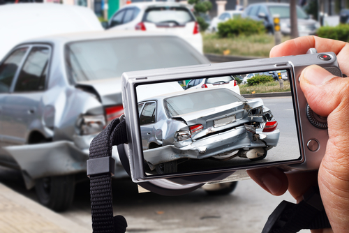 Michigan car accident lawyer image of person photographing rear-end collision damage for accident evidence